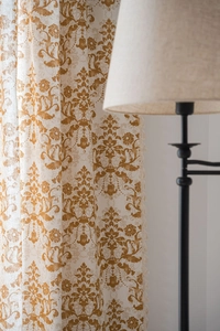 Close-up of khaki damascus print curtains with elegant tassel trim in a cozy room