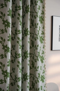 Dettaglio del tessuto jacquard grigio con motivi a foglie verdi e bordi con nappe