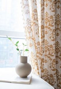 Detail of khaki damascus print curtain featuring decorative cream tassel fringe trim