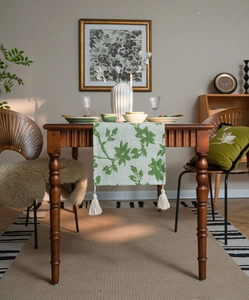 Detail of floral jacquard table runner with green leaves and elegant white tassel