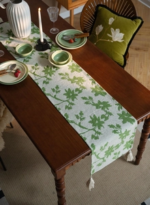 Detail of Nordic jacquard floral table runner with white fringe tassels on wooden table