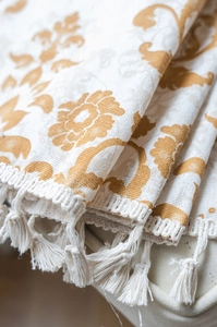 Detail of khaki damask printed curtain fabric featuring elegant cream tassels on the edge