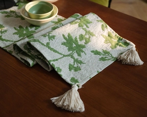 Detail of Nordic jacquard table runner featuring green leaf print and white tassel trim