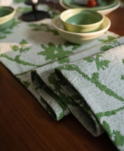 Close-up of jacquard table runner with green leaf patterns and thick woven texture