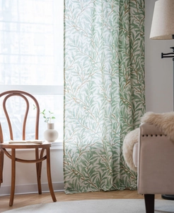 Detail of green leaf print curtains in a sunlit room featuring soft natural lighting