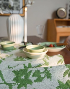 Detail of floral jacquard table runner with green leaf pattern and tassel texture