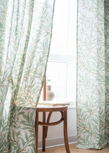 Detailed texture of cotton linen curtain with green leaf print in soft natural sunlight