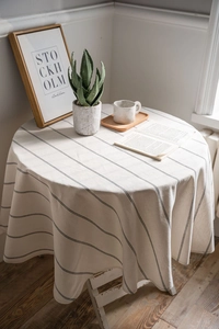 Close-up of beige linen round tablecloth with minimalist black stripes and natural texture