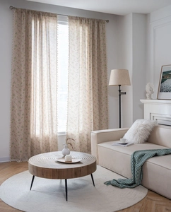 Detail of semi-sheer floral curtain with beige fringe tassels in a modern living room