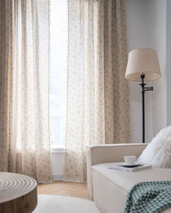 Detail of floral print curtains with decorative fringe tassels in a cozy home setting