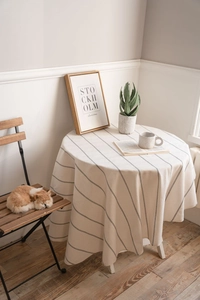 Close-up of cream cotton linen tablecloth with fine stripes on a round dining table