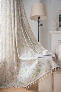 Detail of floral linen curtains with green leaves and decorative white tassels