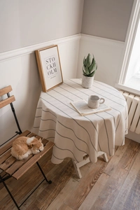 Detailed view of beige cotton linen round tablecloth with black thin vertical stripes