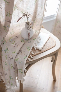 Detail of floral print linen curtain featuring elegant white tassel fringe and pastel blooms