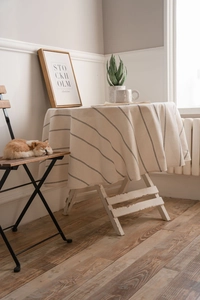 Detailed view of striped round linen tablecloth draped over a wooden table in a home setting