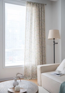 Detailed view of floral print semi-sheer curtain fabric with elegant fringe tassels decoration