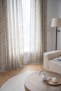 Detail of floral print curtains with beige tassel trim and light-filtering linen fabric