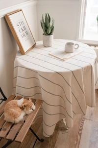 Close-up of cream linen round tablecloth with black stripes showing elegant soft drape