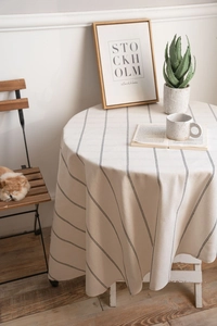 Detailed view of striped linen round tablecloth in a cozy home setting with coffee cup