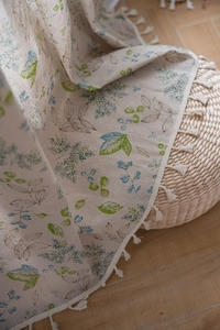 Close-up of green leaf floral printed curtain fabric with delicate beige tassels