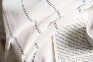 Close-up of beige linen tablecloth with blue stripes showing soft fabric texture and drape