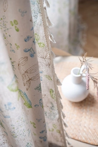 Detail of green leaf floral print curtain with white tassel trim on linen fabric