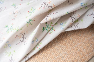 Detail of floral printed linen fabric with delicate small blossoms on woven mat background