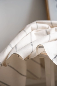 Close-up of cream beige striped cotton linen fabric with vertical blue stripes texture