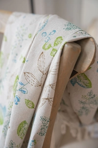 Close-up of cotton linen fabric with fresh green leaf prints and natural fiber texture