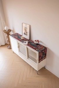 Detail of bohemian red jacquard table runner with geometric patterns and handmade tassels