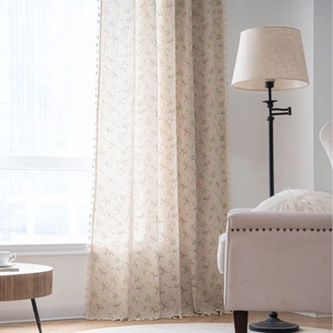 Beige floral print linen curtain with tassel fringe edges in a bright living room setting