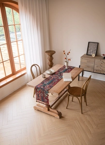 Detail of red jacquard table runner with bohemian patterns and fringe on wooden table