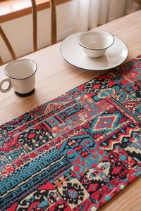 Close-up of bohemian woven table runner with red geometric jacquard pattern and fringes