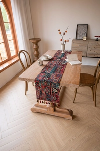 Close-up of bohemian geometric jacquard table runner with red tassels on wooden table