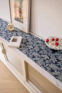 Close-up of Nordic table runner with blue jacquard leaf patterns and woven fabric texture