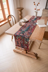 Close-up of red geometric jacquard table runner with colorful fringe on wood table