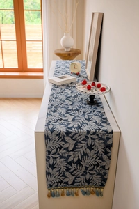 Detail of blue leaf jacquard table runner with decorative woven fringe tassels