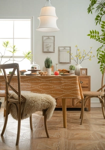 Detailed texture of mustard orange linen tablecloth with white floral and vine patterns