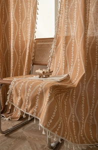 Detail view of bohemian curtains with white floral vine prints and elegant white fringe trim