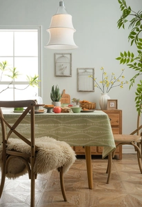 Detailed close-up of light green cotton linen tablecloth with white floral vine prints