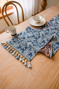 Detail of Nordic blue table runner showing dense leaf weave and colorful fringe tassels