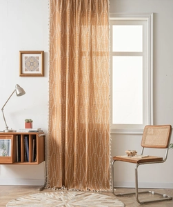 Detail of bohemian curtain featuring white floral patterns and tassel edges on ochre fabric