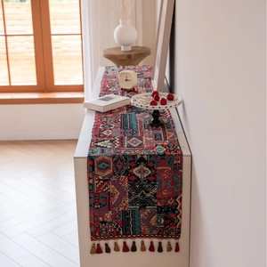 Bohemian geometric jacquard table runner with colorful tassels on a white cabinet
