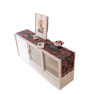 Bohemian geometric red table runner with colorful tassels on a vintage white sideboard cabinet