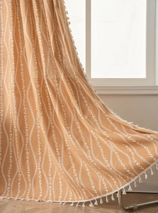Detail of yellow cotton linen curtain with white floral patterns and tassel trim