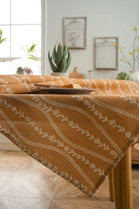 Detailed close-up of orange floral cotton linen tablecloth with white botanical patterns