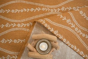 Detailed close-up of mustard yellow linen tablecloth with white floral pattern texture