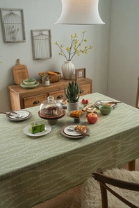 Detailed close-up of light green floral cotton linen tablecloth in a rustic dining setting