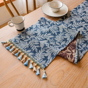 Nordic blue leaf pattern table runner with tassels on a wooden dining table