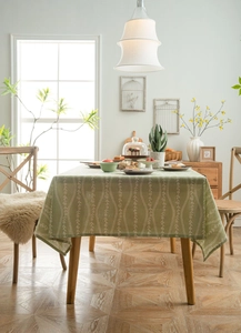 Detailed close-up of light green floral linen tablecloth with white vine patterns